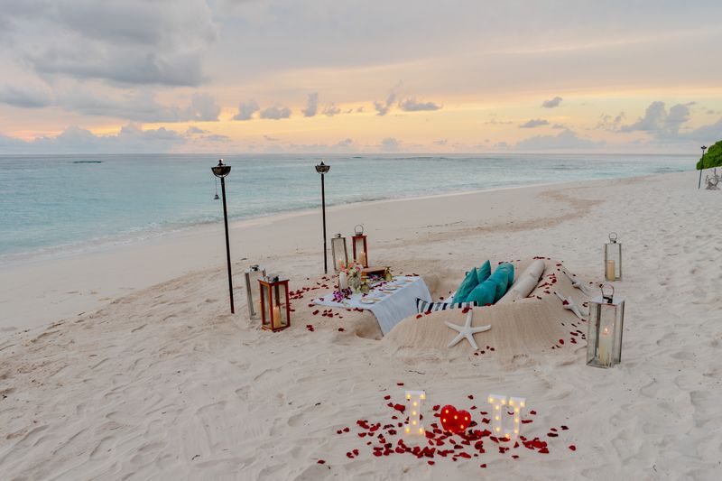 Candlelit table for two set on the sand at sunset