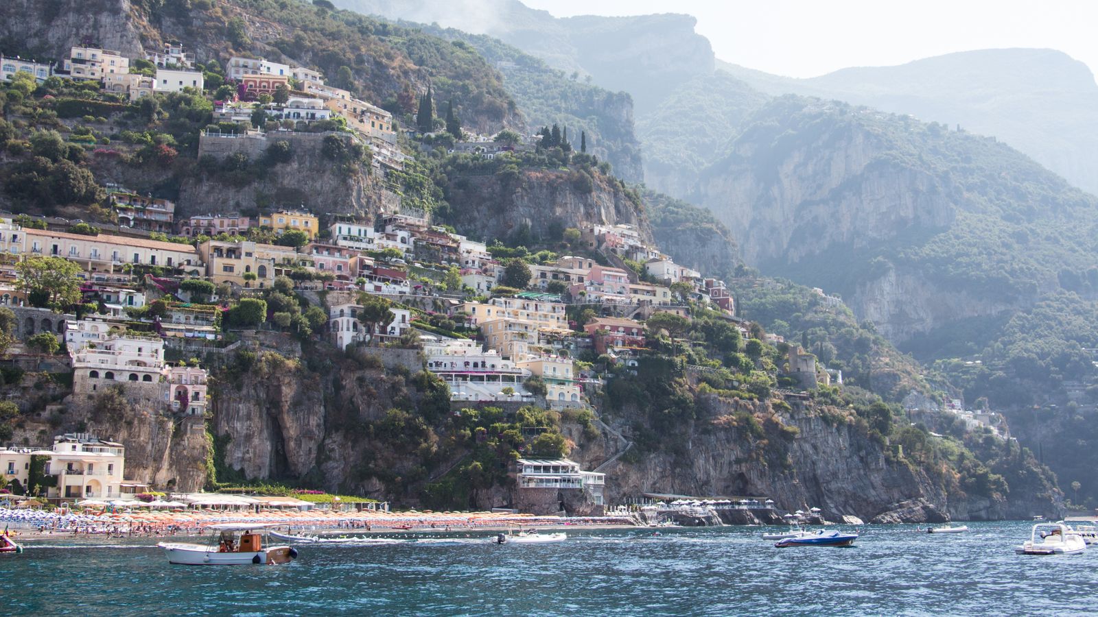 Positano harbor boats below cliffs