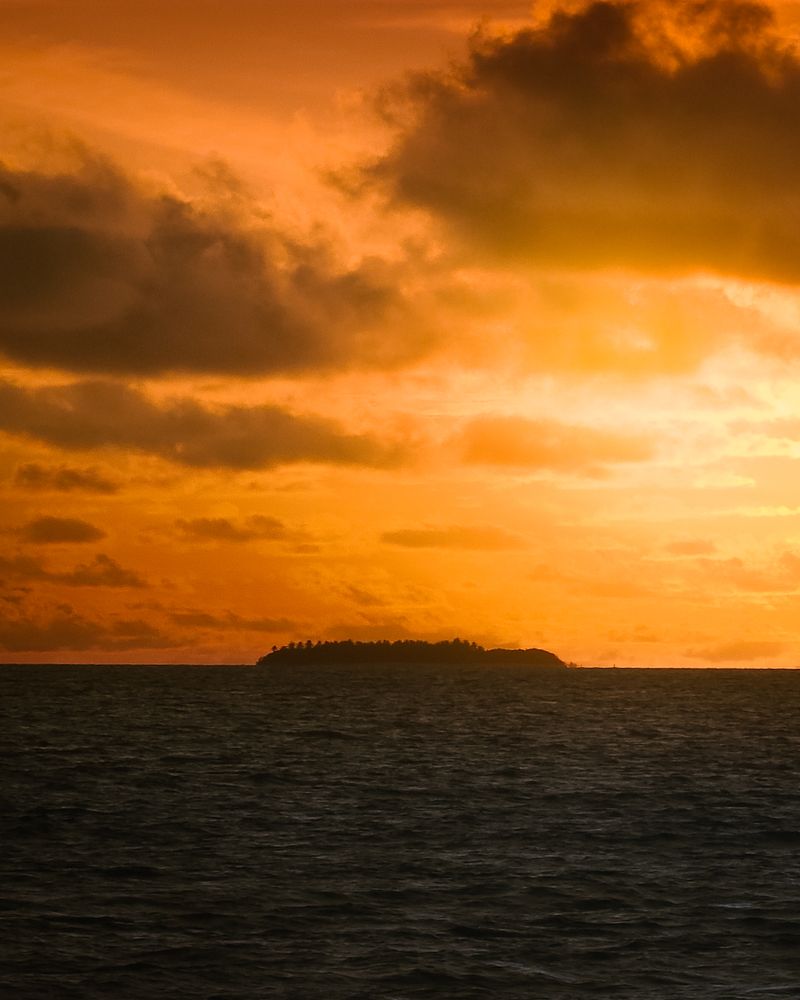 Tropical island silhouetted against a South Pacific sunset