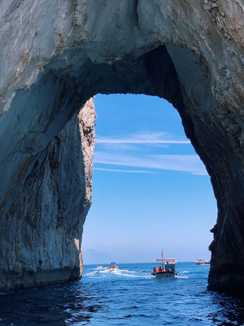 Boats passing through a natural sea arch